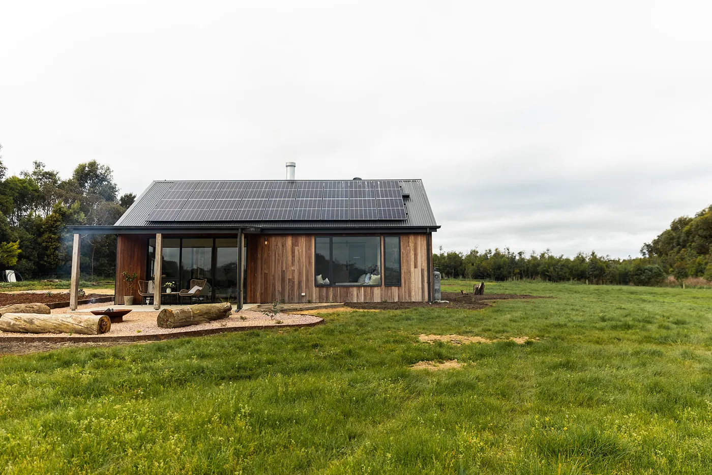 The Forever Held retreat in its paddock, with solar panels on the roof and a fire pit out front