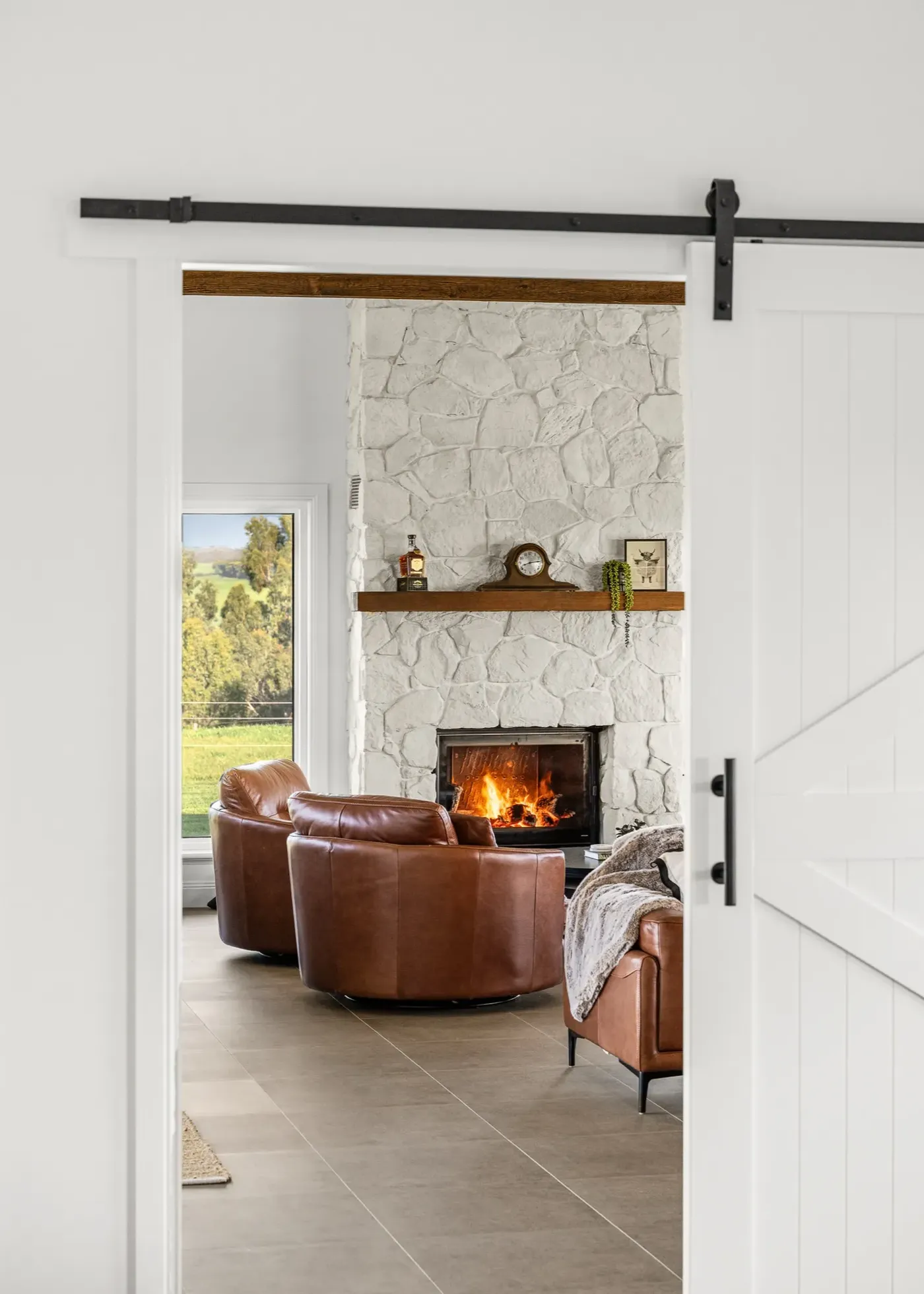 Renovated lounge with stone fireplace and barn door
