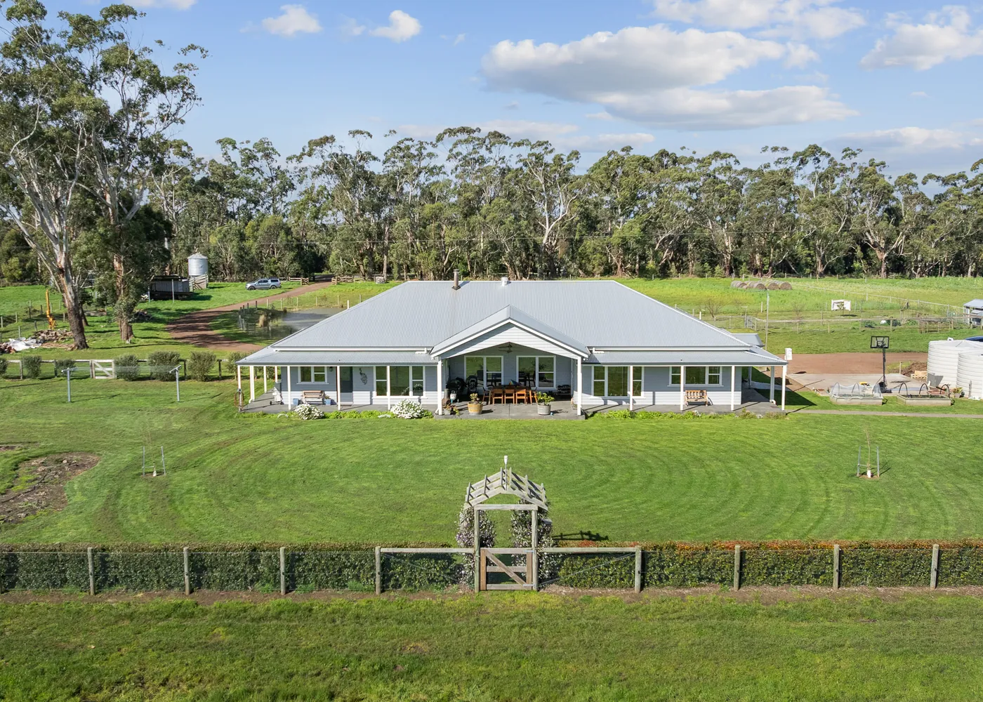 Laang Farmhouse from above, a weatherboard farmhouse wrapped in verandahs with gums behind